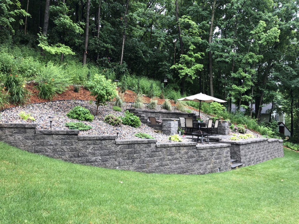 Outdoor living area carved out of a steep slope with retaining walls and custom block steps