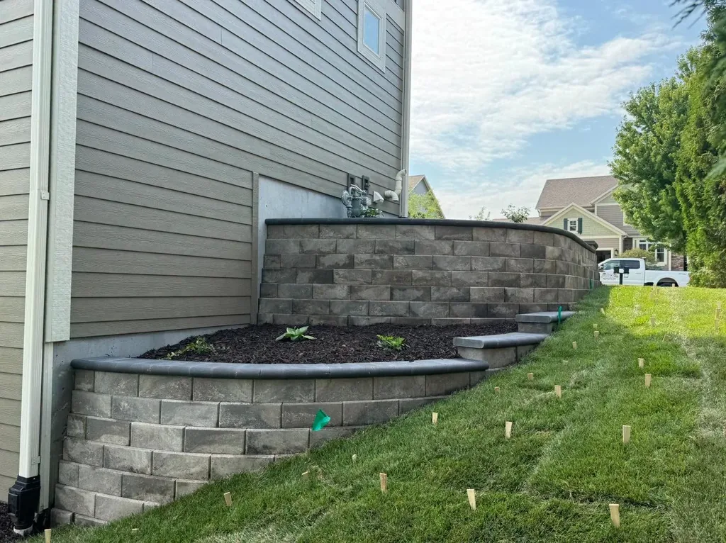 Block retaining wall and raised planting bed beside a house